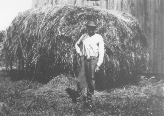 Roy Wilcox in front of his barn with a loose load of hay